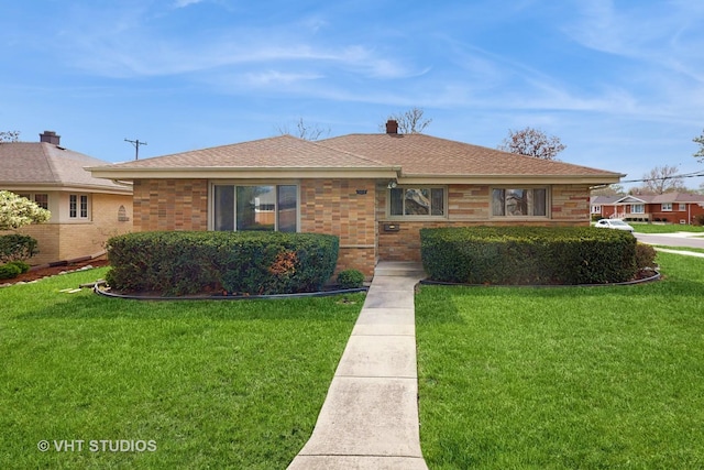 view of front of home featuring brick siding, a shingled roof, and a front lawn