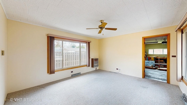 carpeted spare room with heating unit and ceiling fan