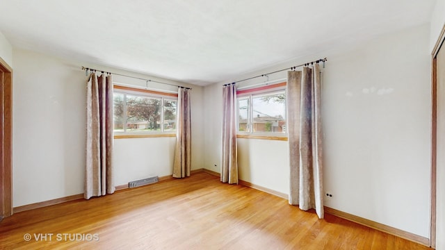 unfurnished room featuring baseboards, visible vents, a healthy amount of sunlight, and light wood-style flooring