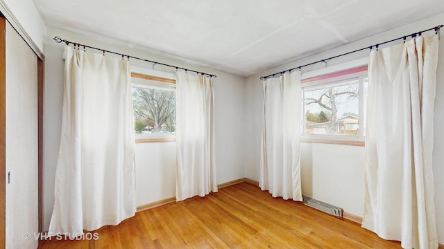 empty room with visible vents, light wood-style flooring, and baseboards