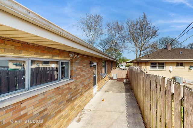 view of side of home with brick siding and fence