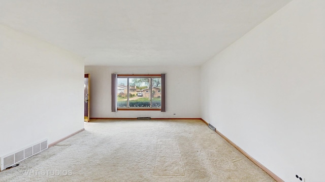 empty room featuring baseboards, light colored carpet, and visible vents