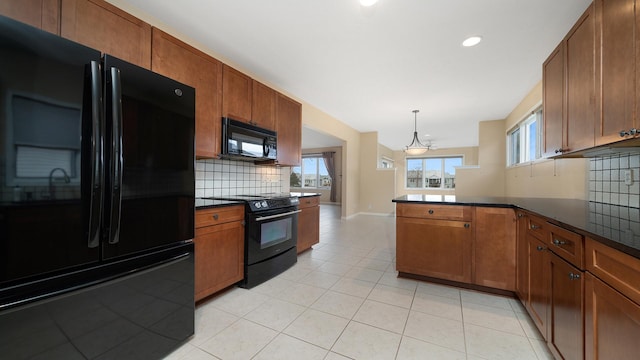 kitchen with dark countertops, tasteful backsplash, brown cabinets, black appliances, and a peninsula