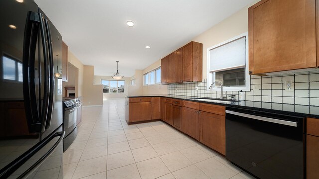 kitchen featuring brown cabinets, a sink, decorative backsplash, light tile patterned floors, and black appliances