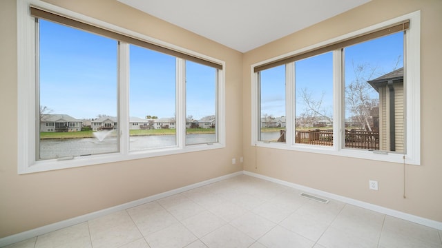 spare room with baseboards, a water view, a healthy amount of sunlight, and visible vents