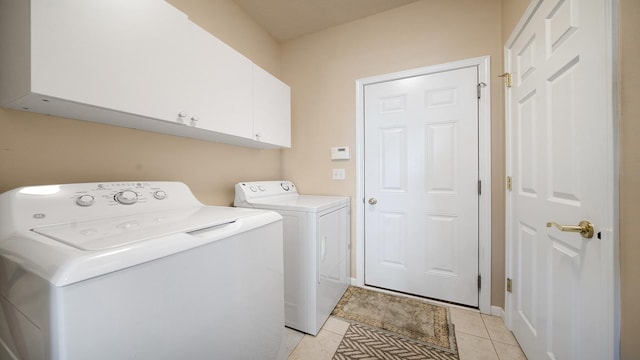 washroom featuring washing machine and dryer, cabinet space, and light tile patterned flooring