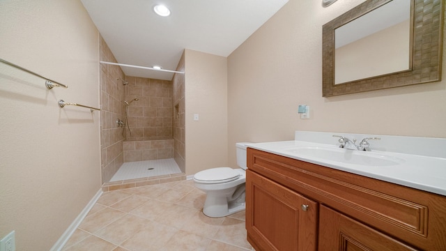 full bath featuring vanity, tile patterned flooring, toilet, baseboards, and a tile shower