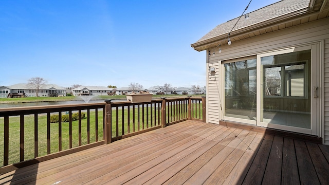 wooden terrace with a water view, a yard, and a residential view