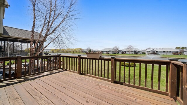 wooden terrace featuring a residential view, a water view, and a lawn