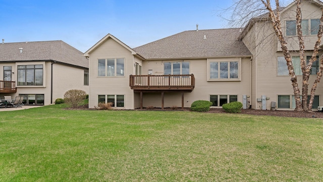 back of house featuring a wooden deck, a shingled roof, and a yard