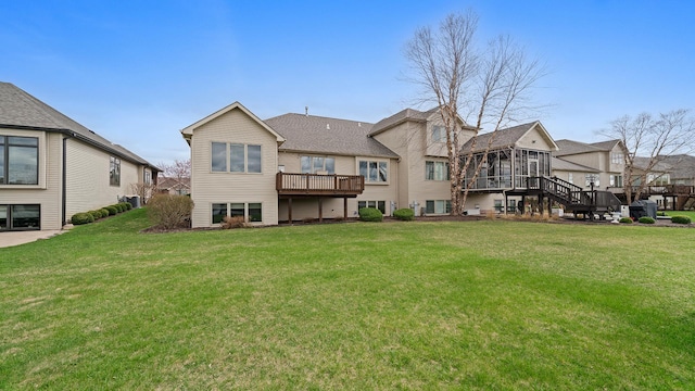 back of property featuring a residential view, a sunroom, a deck, stairway, and a yard