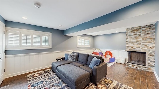living area featuring a large fireplace, wood finished floors, and a wainscoted wall