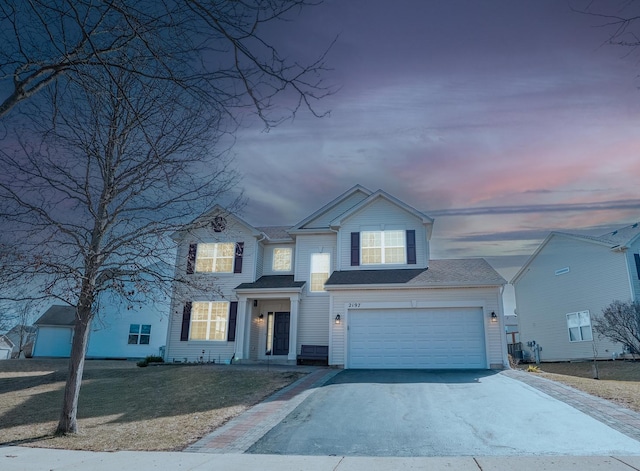 traditional-style home with a garage, aphalt driveway, and a yard