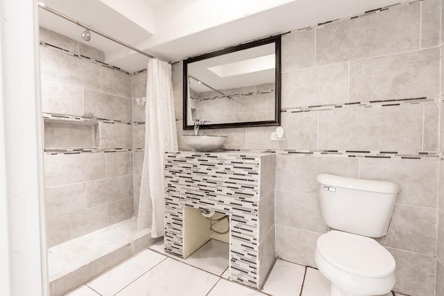 bathroom featuring a sink, tile walls, a tile shower, and toilet