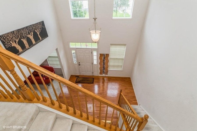 foyer entrance with a towering ceiling, baseboards, and stairway