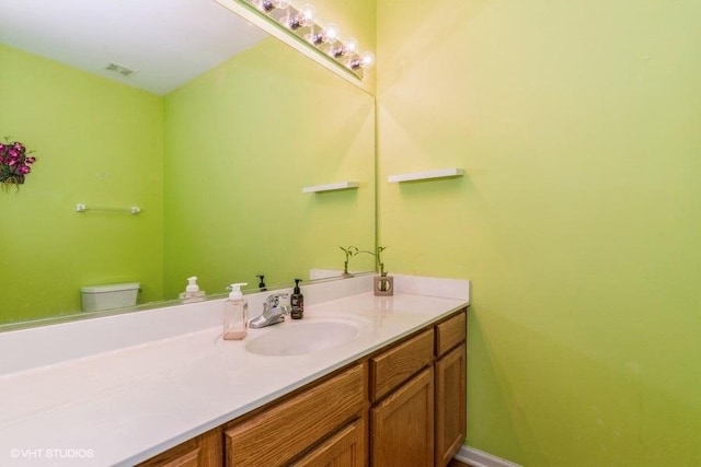 bathroom featuring toilet, vanity, and visible vents