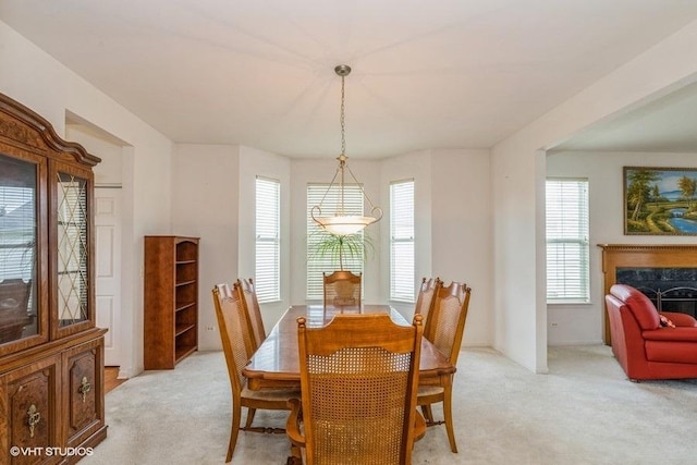 dining area featuring light carpet and a fireplace