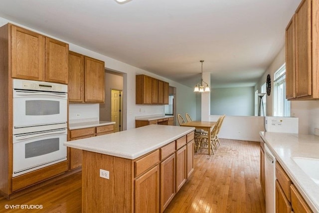 kitchen with light countertops, light wood-style flooring, white appliances, and a chandelier