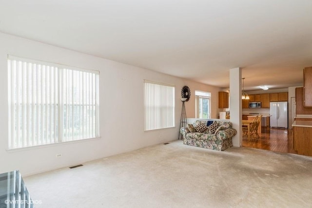 carpeted living room featuring a wealth of natural light and visible vents