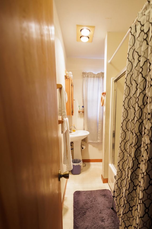 bathroom featuring tile patterned floors, shower / tub combo with curtain, and baseboards