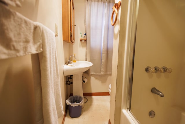 full bathroom featuring toilet, washtub / shower combination, tile patterned floors, and baseboards