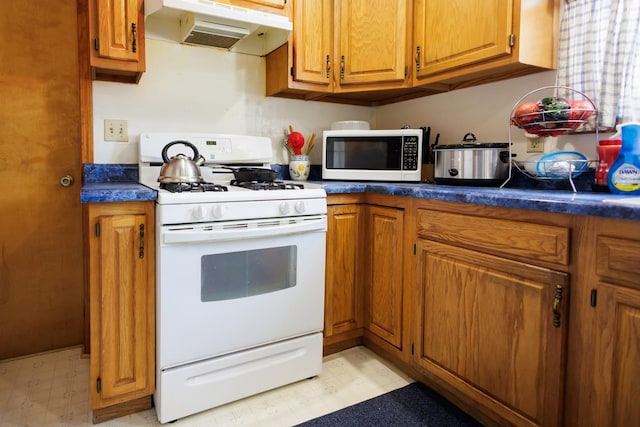 kitchen featuring brown cabinetry, white appliances, light floors, and under cabinet range hood