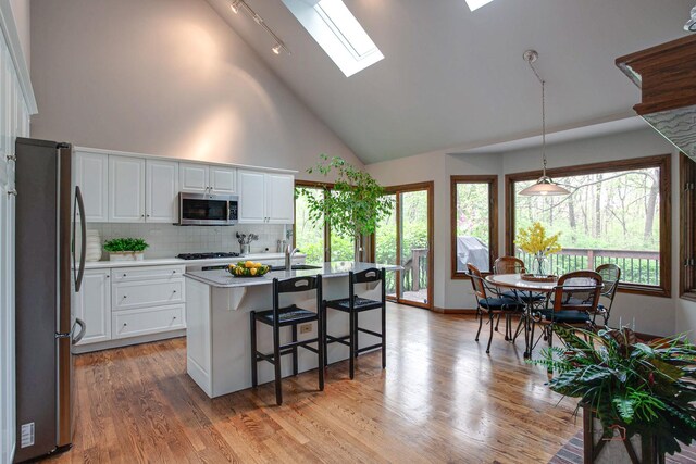 16737 W Cherrywood Ln, Wadsworth, IL 60083 - kitchen featuring high vaulted ceiling, light wood-style flooring, white cabinetry, a skylight, and appliances with stainless steel finishes