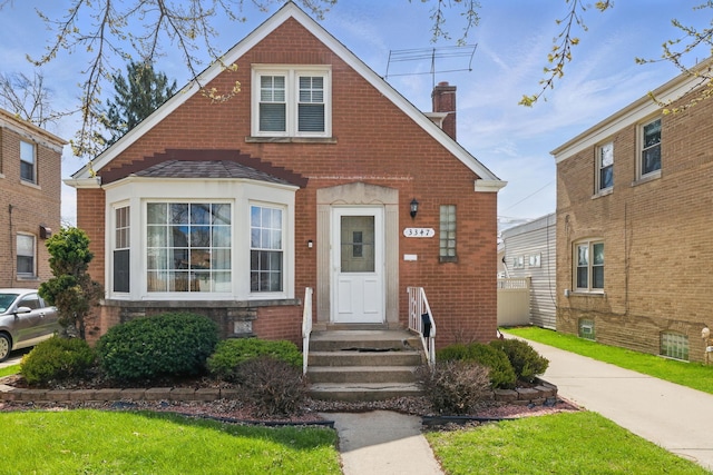 view of front facade featuring a chimney and brick siding