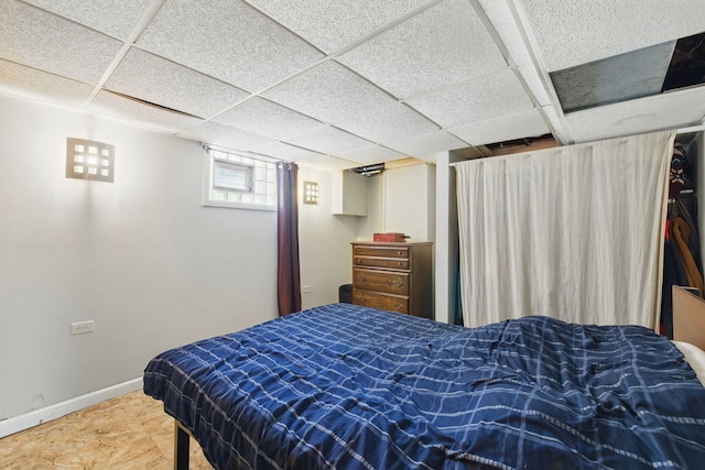 bedroom with a paneled ceiling and baseboards