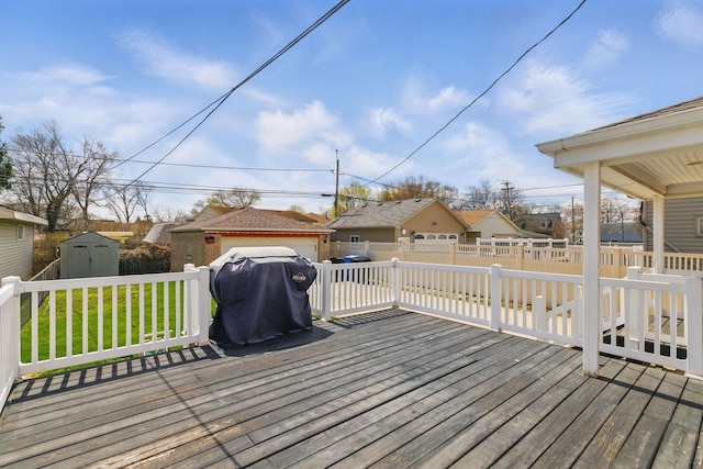 wooden terrace featuring fence, a residential view, an outdoor structure, a lawn, and a storage unit