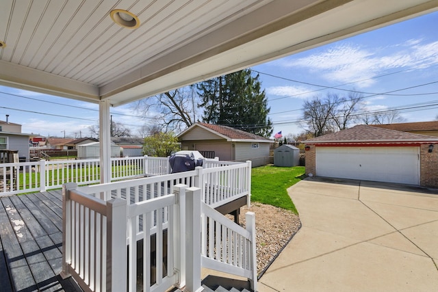 deck with fence, an outbuilding, a detached garage, a lawn, and a storage unit
