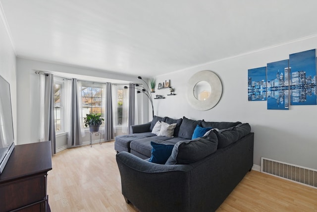 living room featuring visible vents, light wood finished floors, and baseboards