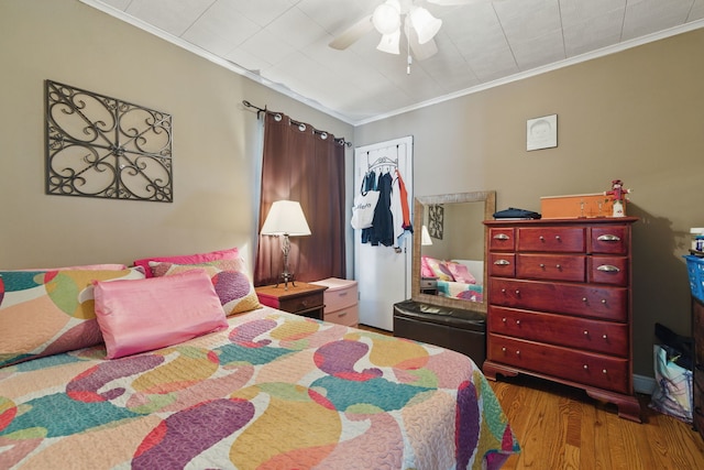 bedroom featuring wood finished floors, a closet, a ceiling fan, and ornamental molding