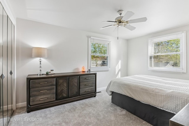 bedroom with light colored carpet, baseboards, a closet, and a ceiling fan