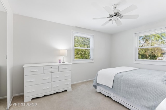 bedroom featuring light carpet, baseboards, and ceiling fan