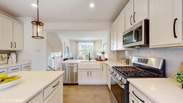 405 Filson St, La Grange, IL 60525 - kitchen with backsplash, a sink, white cabinets, stainless steel appliances, and light wood-style flooring
