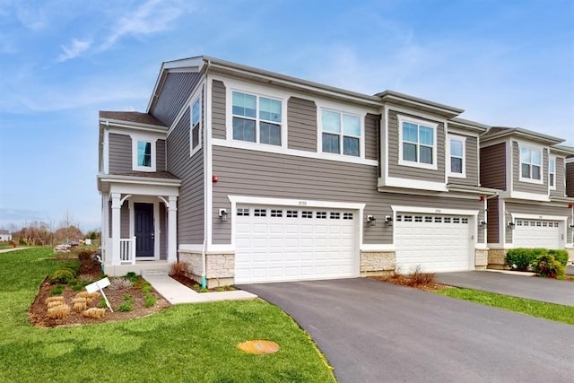 view of front of property with stone siding, a front yard, driveway, and a garage