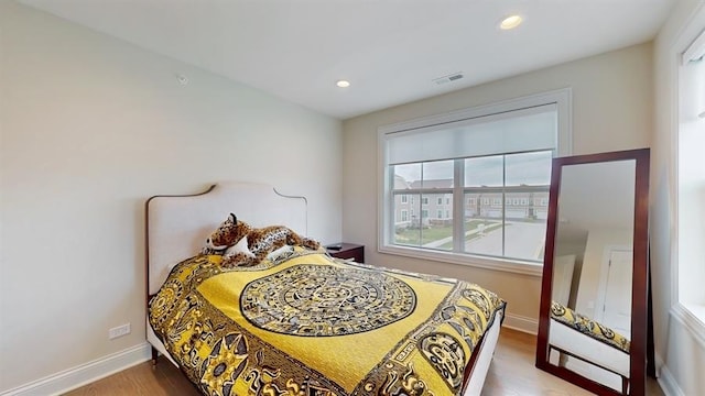 bedroom featuring wood finished floors, baseboards, visible vents, and multiple windows