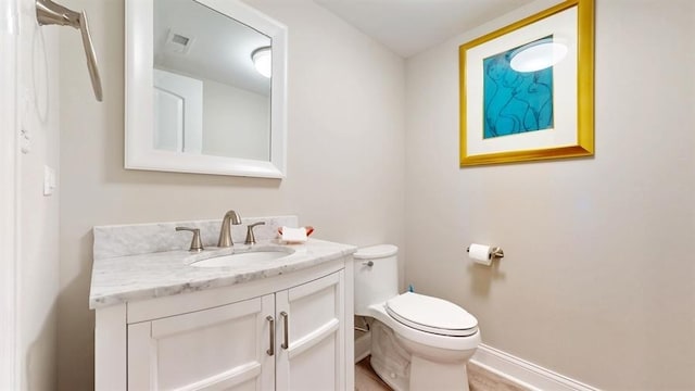 bathroom with toilet, baseboards, and vanity