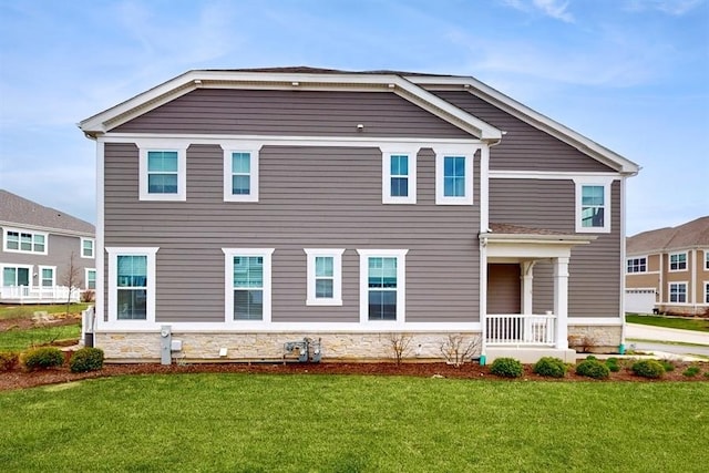 view of front facade with stone siding and a front lawn