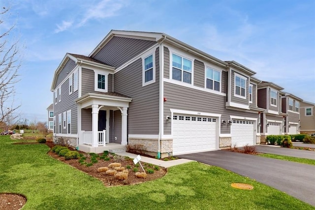 view of front of property with covered porch, stone siding, driveway, a garage, and a front lawn