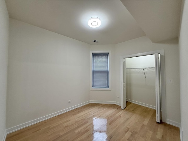 unfurnished bedroom featuring light wood-style flooring, a closet, and baseboards
