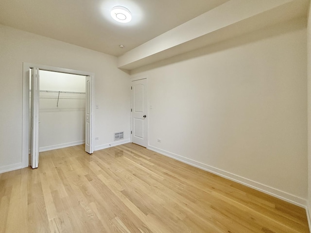 unfurnished bedroom featuring visible vents, light wood-style flooring, a closet, and baseboards