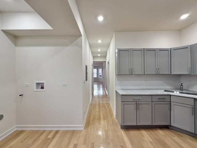 clothes washing area with light wood-style flooring, recessed lighting, washer hookup, and baseboards
