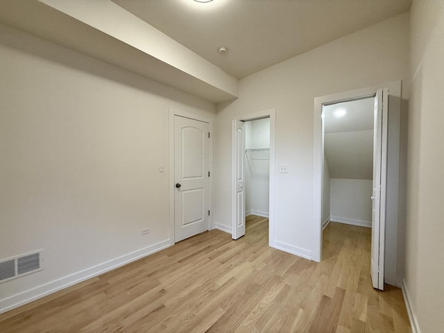 unfurnished bedroom featuring visible vents, baseboards, a closet, a spacious closet, and light wood finished floors