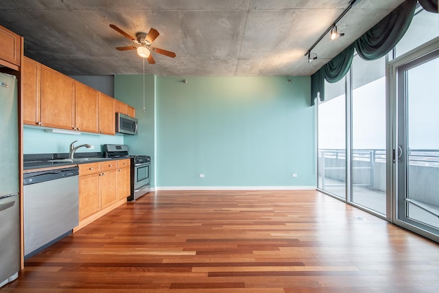 kitchen featuring appliances with stainless steel finishes, wood finished floors, a sink, and dark countertops