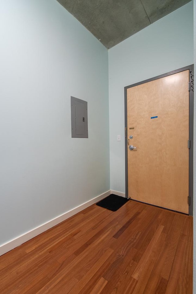 interior space with electric panel, baseboards, and wood finished floors