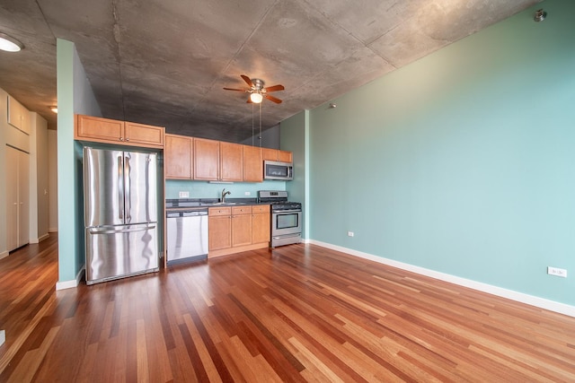kitchen with baseboards, a sink, a ceiling fan, dark wood-style floors, and stainless steel appliances