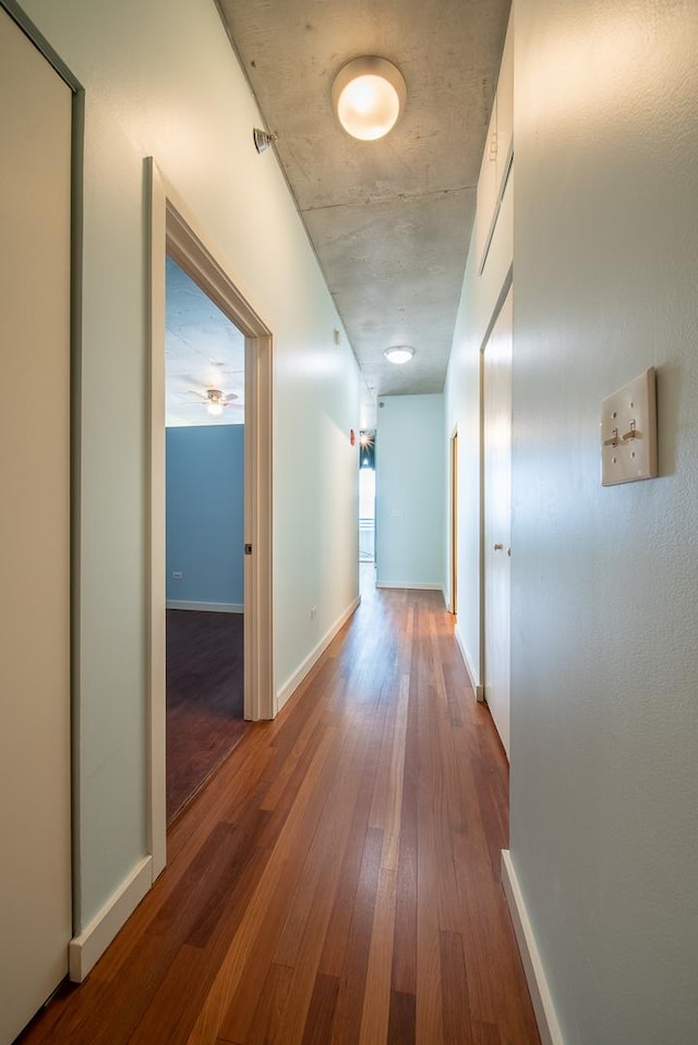corridor with wood-type flooring and baseboards