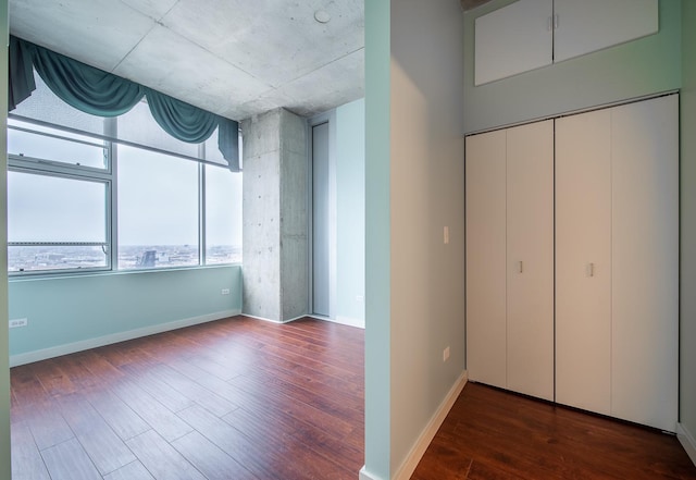 unfurnished bedroom with a closet, baseboards, multiple windows, and wood finished floors